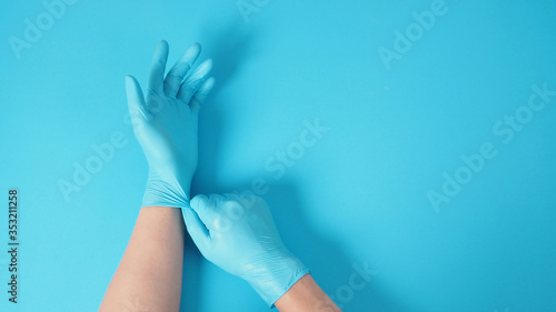 Right hand is pulling blue latex gloves of left hand on blue background.