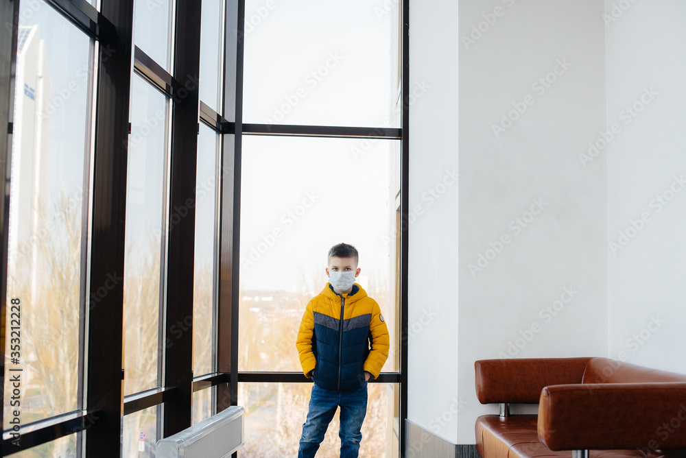 A boy stands on a gray background in a mask during a quarantine with free space. Quarantine in the mask A boy stands on a gray background in a mask during a quarantine with free space. Quarantine in the mask