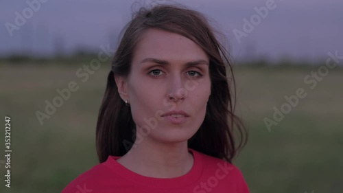 Portrait of beautiful woman in red sweatshirt , looking at the camera in summer. Close-up. The squally wind fan the girl's hairs.