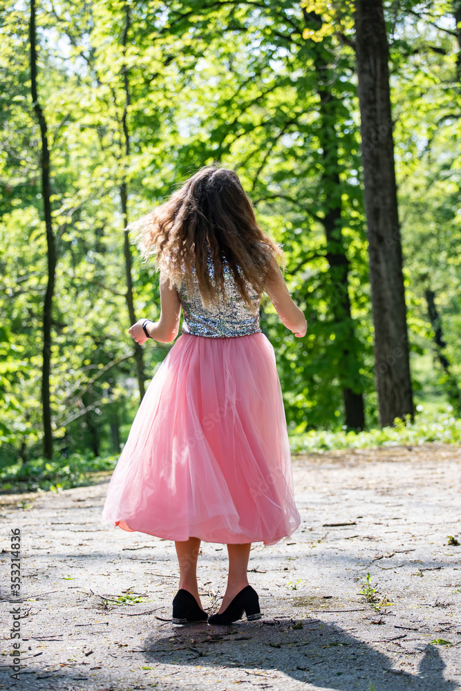 young woman walking in the park in a pink dress