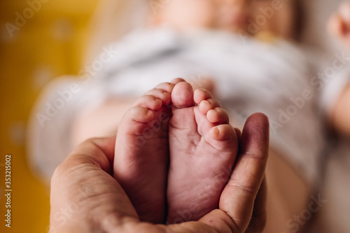 Baby feet holding by parents hand with baby defocused photo