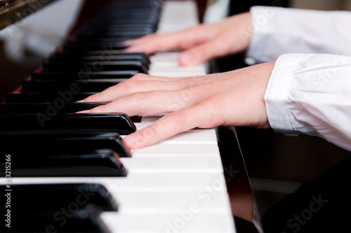 a schoolgirl in a white shirt plays the piano keys. selective focus © Наталья Маяк