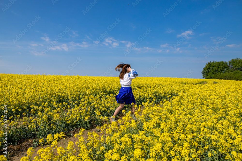 young woman running in a field with yellow flowers, blue sky, space young woman running in a field with yellow flowers, blue sky, space