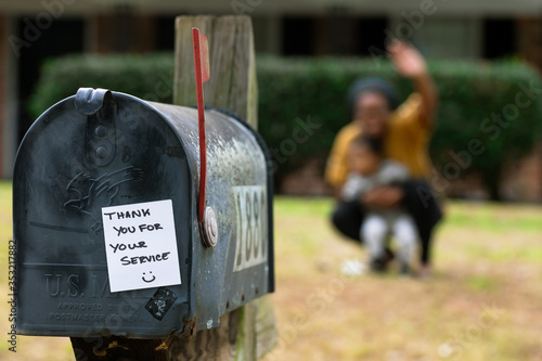 Family waiving to essential worker postal delivery people at home from a safe distance