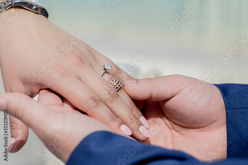 Bride and groom exchanging wedding rings close up during symbolic nautical decor destination wedding marriage on sandy beach in front of the ocean in Punta Cana, Dominican republic  © Irina