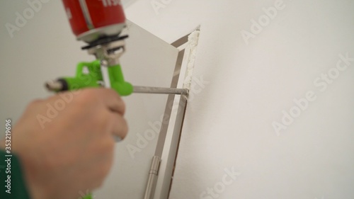 the master with the help of mounting foam, repairs the door jamb. The master uses construction foam. young man sets the door. The installer fills the door slope with foam