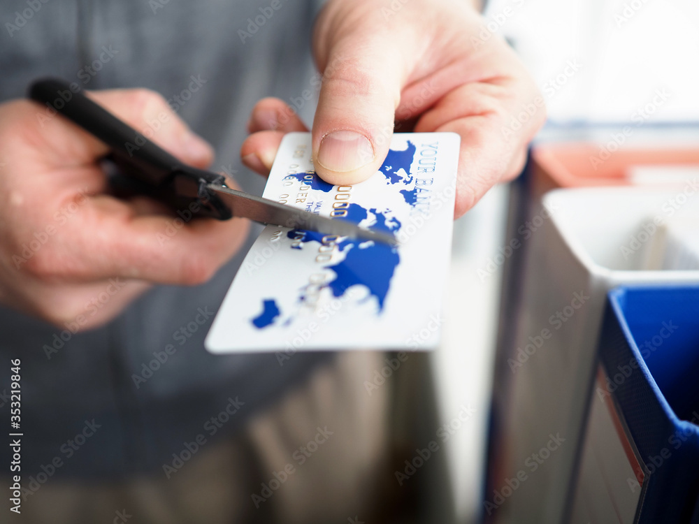 Male hand cutting banking card with scissors Male hand cutting banking card with scissors