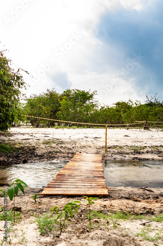 Pequena ponte de madeira sobre o riacho estreito em uma das praias de areia branca do rio Tapajós em Pindobal, estado do Pará, Brasil. photo