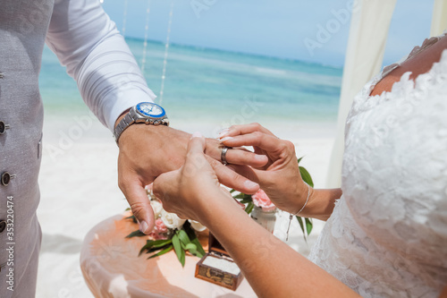 Bild auf Leinwand Bride and groom exchanging wedding rings close up during symbolic nautical decor