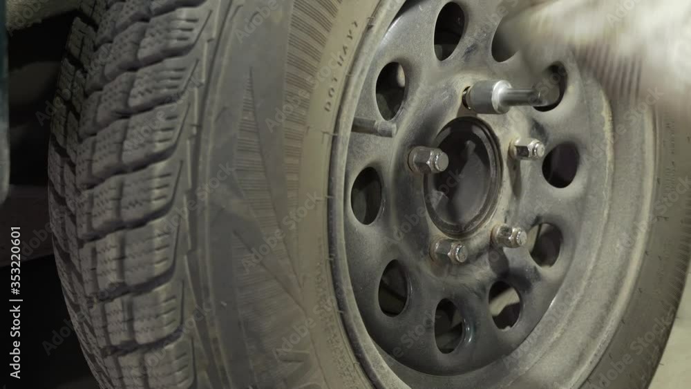 replacing a car wheel, unscrewing and screwing nuts in a garage
replacing a car wheel, unscrewing and screwing nuts in a garage