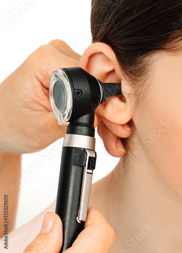 Hearing exam. Otoscope and ear of a child close-up isolated on white. Hearing test in a clinic.