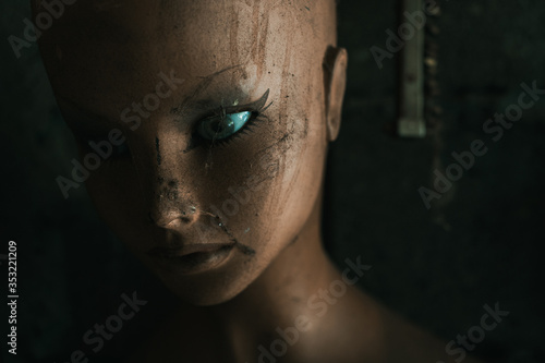 Close-up portrait of an old plastic doll from a shop window standing in a dirty garage photo