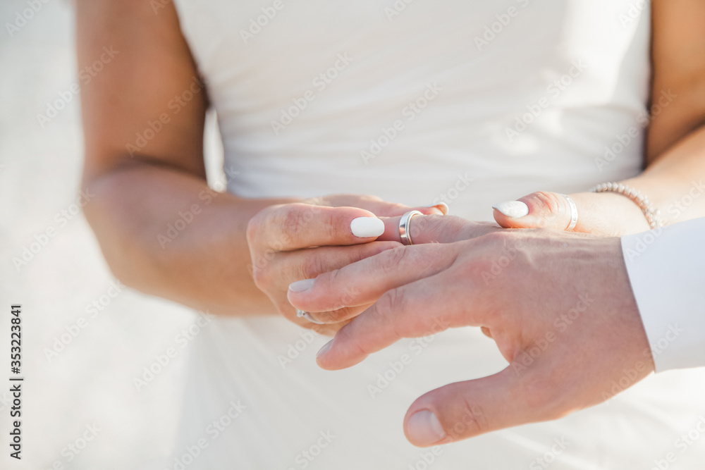 Bride and groom exchanging wedding rings close up during symbolic nautical decor destination wedding marriage on sandy beach in front of the ocean in Punta Cana, Dominican republic Bride and groom exchanging wedding rings close up during symbolic nautical decor destination wedding marriage on sandy beach in front of the ocean in Punta Cana, Dominican republic