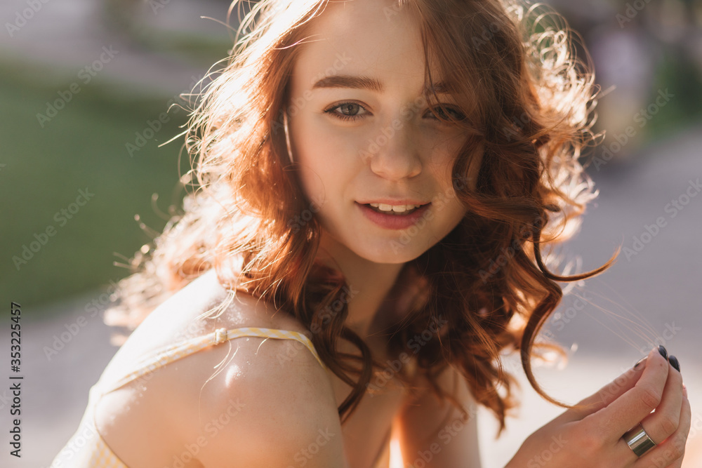 Portrait of romantic ginger girl posing with gently smile on blur nature background. Happy red-haired woman looking to camera in sunny summer morning Portrait of romantic ginger girl posing with gently smile on blur nature background. Happy red-haired woman looking to camera in sunny summer morning