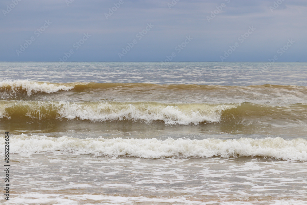 Stormy sea, foaming waves on a empty sandy beach. Atmospheric seascape for background, concept of World oceans day Stormy sea, foaming waves on a empty sandy beach. Atmospheric seascape for background, concept of World oceans day