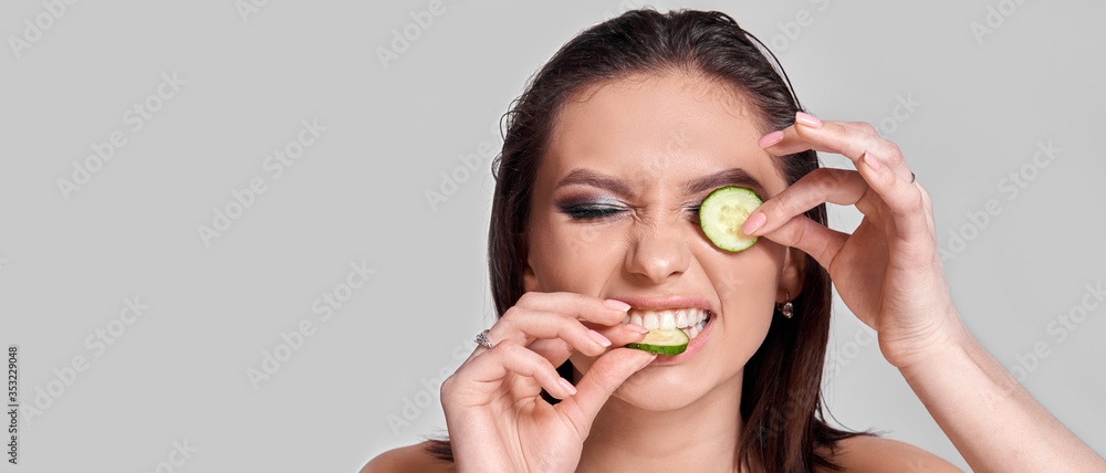 Concept Face care at home. Portrait of young beautiful woman with cucumber on her face Concept Face care at home. Portrait of young beautiful woman with cucumber on her face