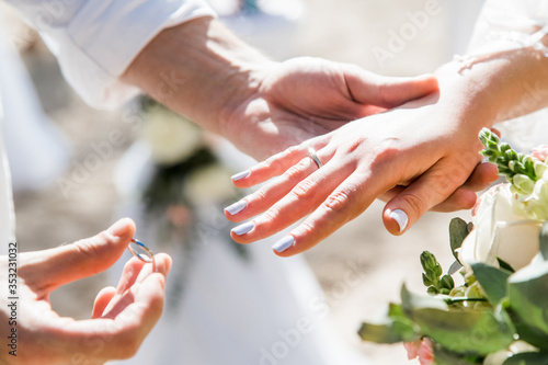 Tableau sur toile Bride and groom exchanging wedding rings close up during symbolic nautical decor