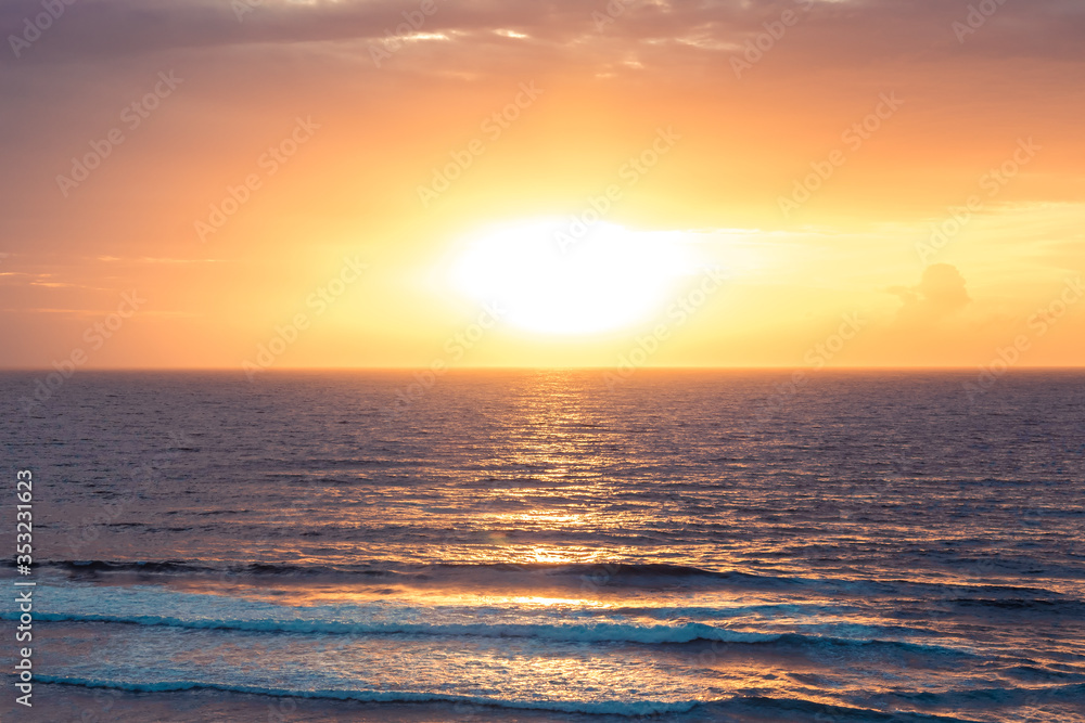 Obraz premium Sea beach surf waves Bali beach Uluwatu surfing spot sunset landscape with cliff view on sea horizon with sun and orange sky as tropical island background