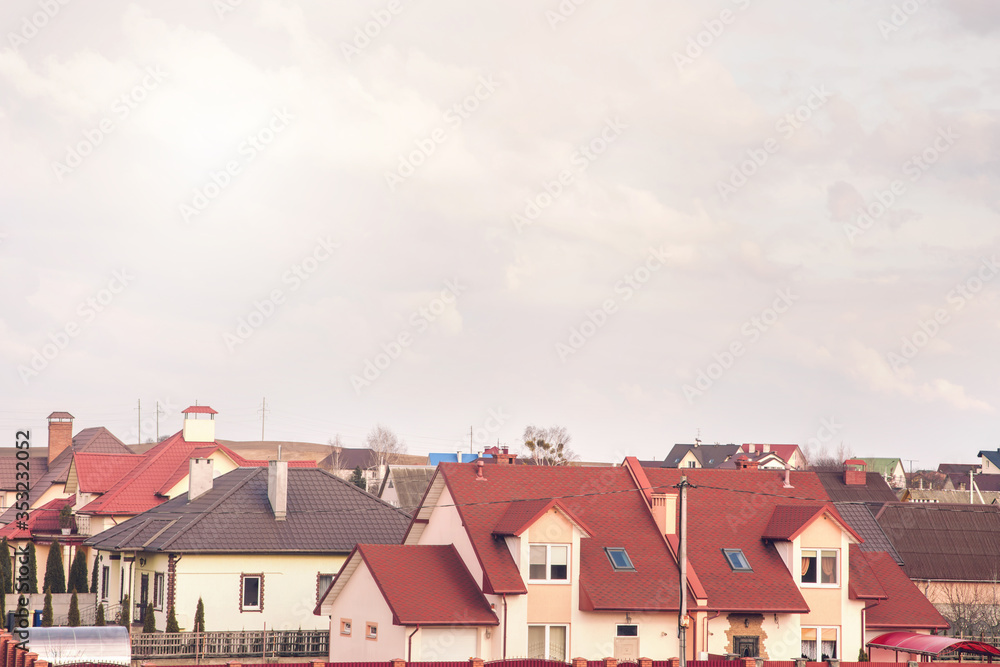 modern cottages with bright roofs in large city district against grey cloudy sky