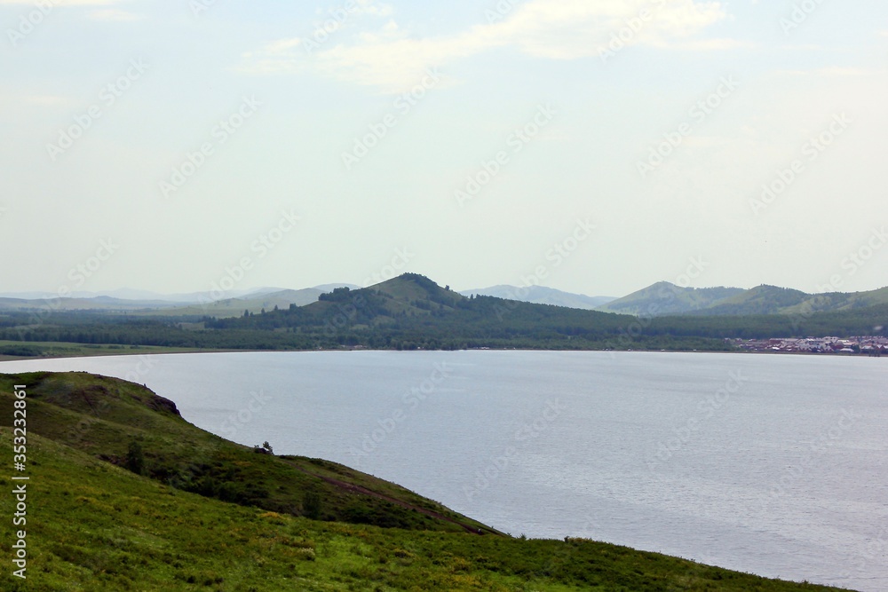 Panoramic view. A lagoon with a clean mountain lake in the midst of majestic mountains in a haze of fog. Green hills in the fog Panoramic view. A lagoon with a clean mountain lake in the midst of majestic mountains in a haze of fog. Green hills in the fog