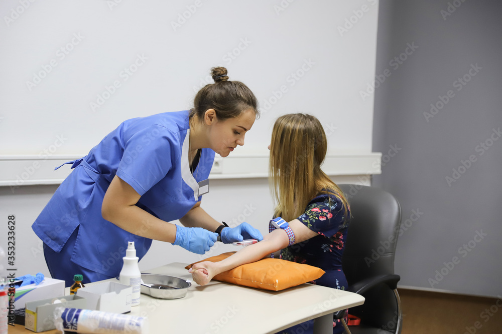 Obraz premium Doctor Injecting patient in arm With Syringe To Collect Blood. Nurse pierce arm vein of a young woman for blood donation/Doctor makes the patient an injection into a vein