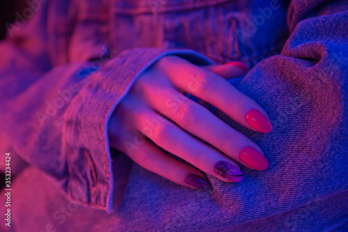 Woman hand with trendy manicure in neon pink light.