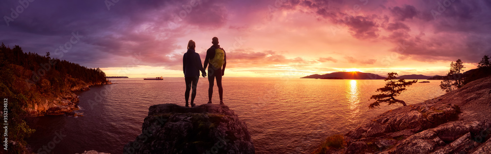 Fantasy Adventure Composite of a Man and Woman Couple on a Rocky Coast during a colorful dramatic sunset. Background taken from Lighthouse Park, West Vancouver, British Columbia, Canada.