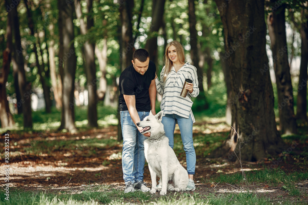 Fototapeta premium Couple in a forest. Pair playing with a cute dog