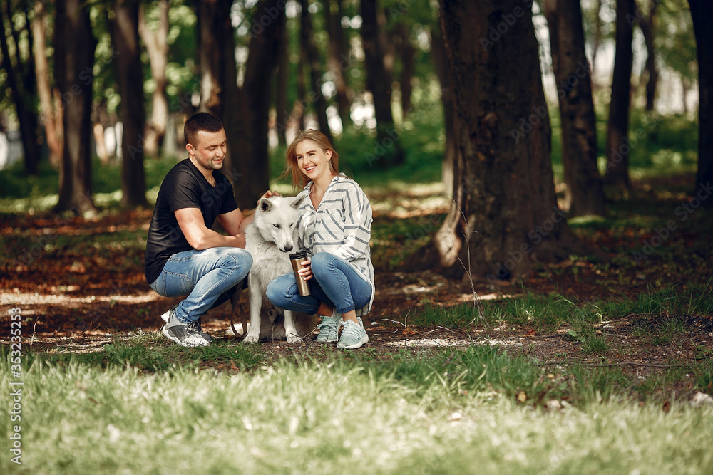 Fototapeta premium Couple in a forest. Pair playing with a cute dog