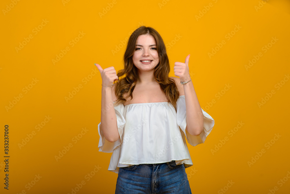 Dark-haired young woman with a smile and big suprised eyes posing on yellow background. Dark-haired young woman with a smile and big suprised eyes posing on yellow background.