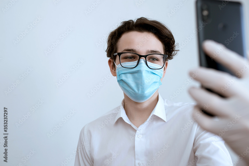 man in a medical mask with a phone in his hands, communicating during quarantine