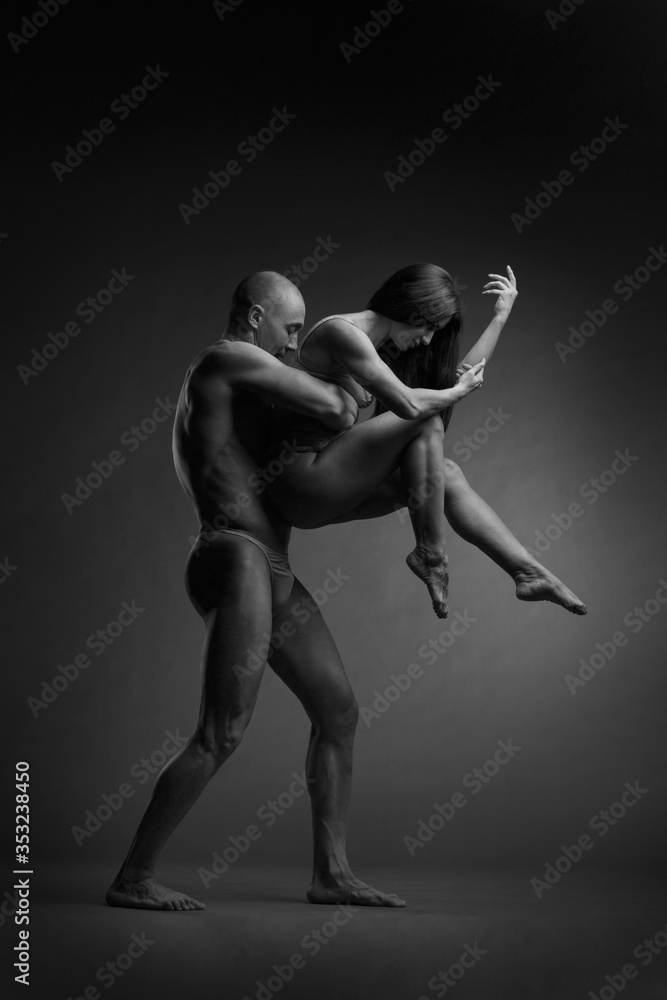 Black and white photo of a pair of dancers in an elegant acrobatic pose against a dark background.