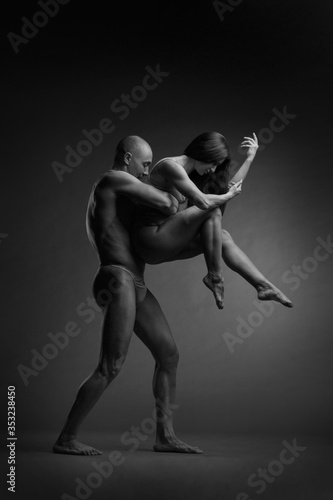 Black and white photo of a pair of dancers in an elegant acrobatic pose against a dark background.