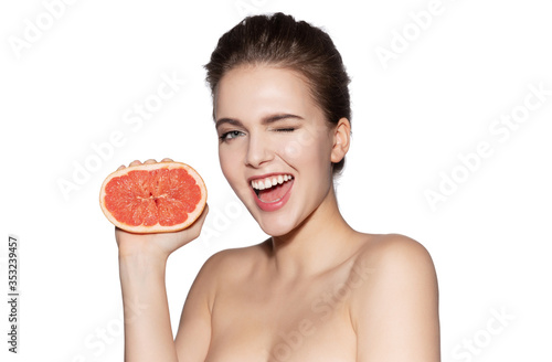 Woman with pure soft skin squeezes fresh grapefruit and laughs. 