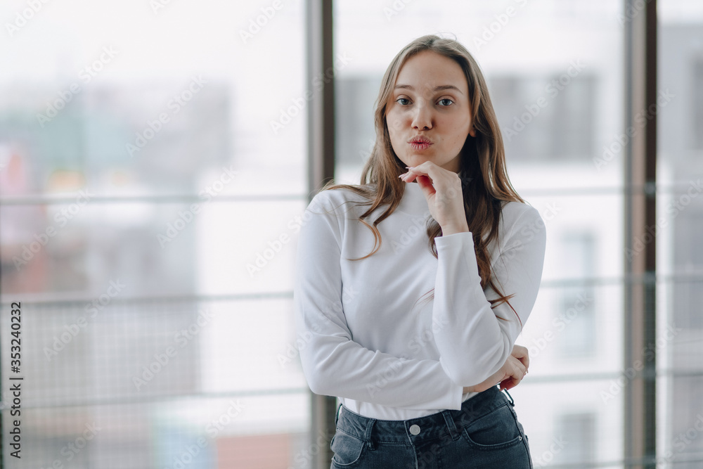 attractive girl on the background of the window shows different emotions and mood. girl on a light background indoors. attractive girl on the background of the window shows different emotions and mood. girl on a light background indoors.