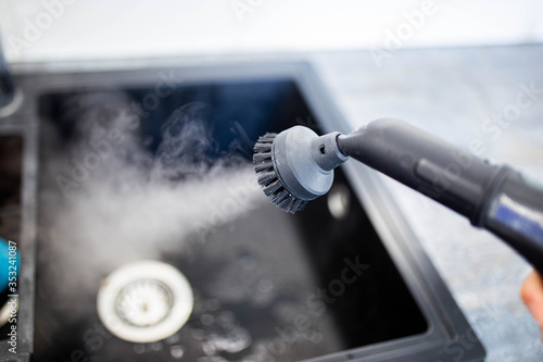 cleaning the sink and faucet with a steam cleaner, disinfection in the house. photo