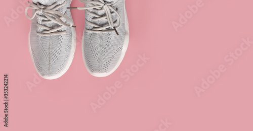 New comfortable sneakers, gray sports shoes with laces on a colored pink background with copy space. Fashion Stylish, beautiful women's shoes for women and teenagers. Minimalism. Flat lay, nobody