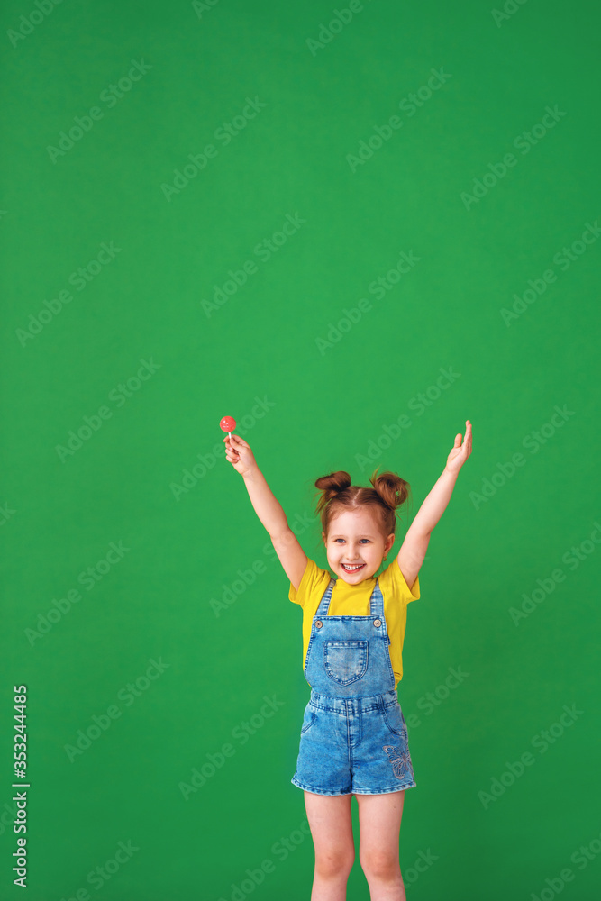 funny child with raised hands in the air. girl with a Lollipop is funny