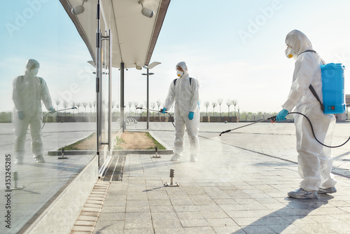 Extreme Cleaning Solutions. Sanitization, cleaning and disinfection of the city due to the emergence of the Covid19 virus. Specialized team in protective suits and masks at work photo