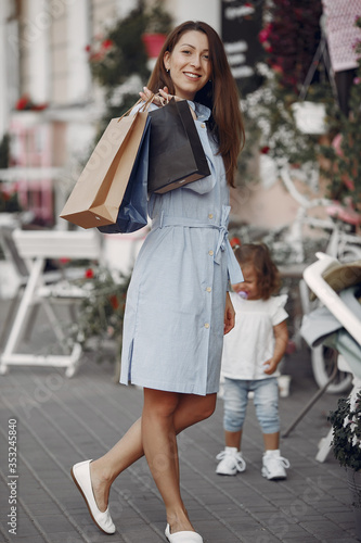 Beautiful girl in a summer city. Lady with shopping bags. Woman in a blue dress