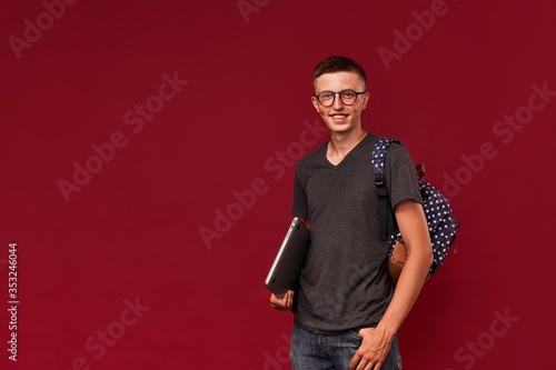 Portrait of a confident student guy with a backpack and laptop