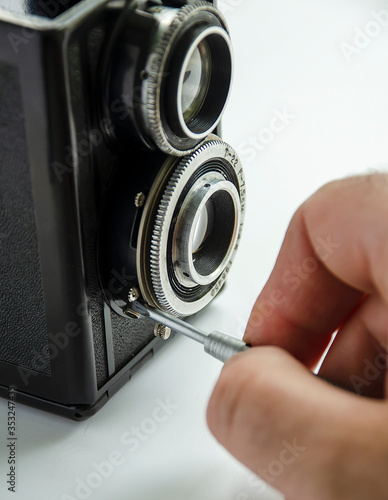 Hand with a screwdriver and an old TLR camera. photo