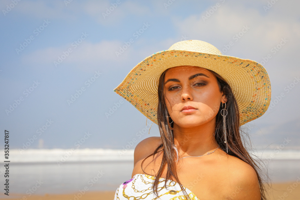 Beautiful young girl in a hat on the ocean.