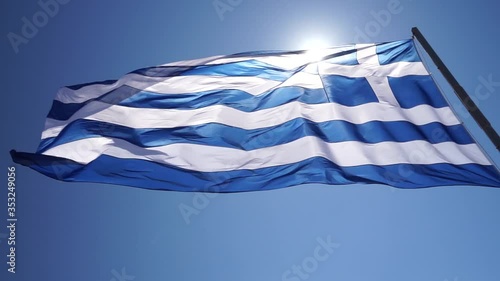 The Greek flag dances in the wind in slow motion, in beautiful Santorini, Greece.