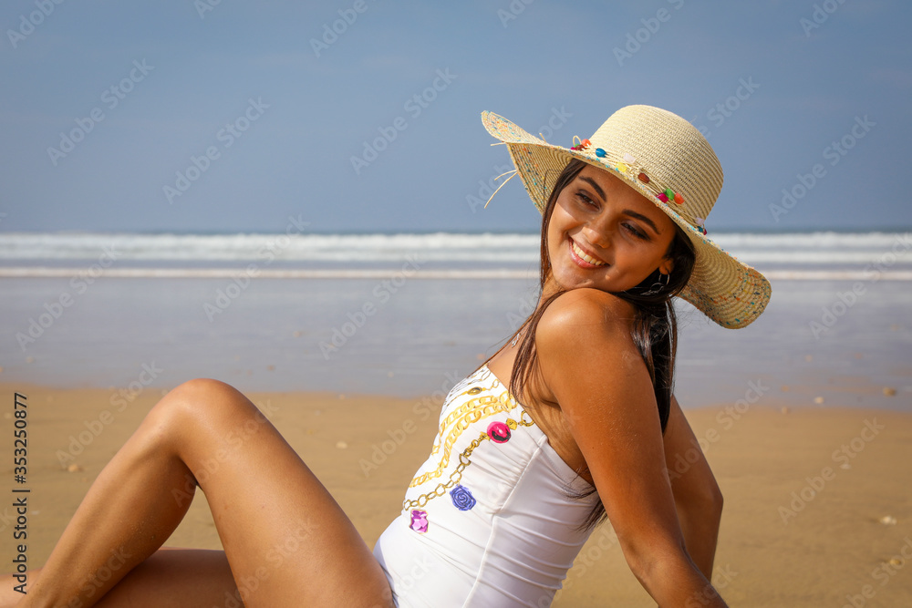 Beautiful young girl in a hat on the ocean.