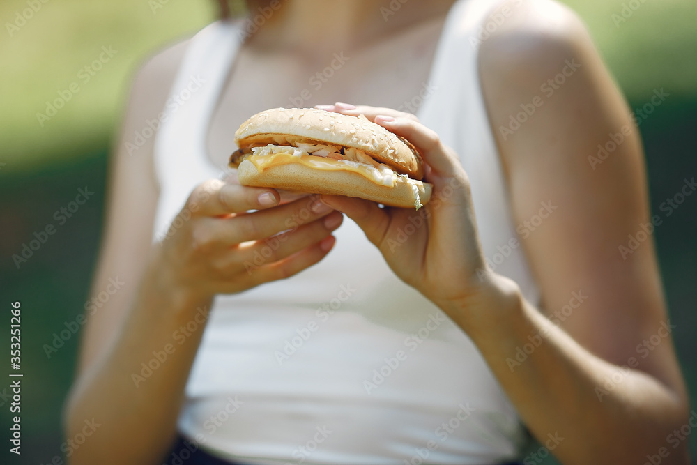 Beautiful girl in a summer park. Lady with a burger Beautiful girl in a summer park. Lady with a burger