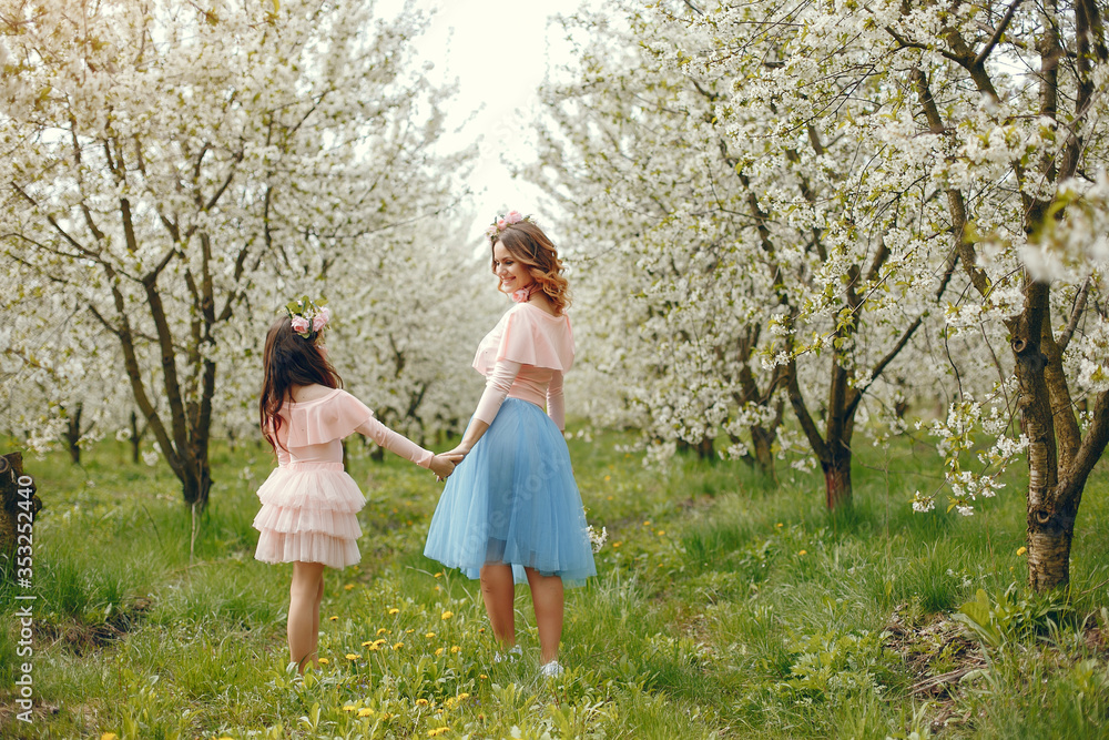 Pretty mother with daughter. Family in a spring park. Woman in a pink dress. Child with a flowers Pretty mother with daughter. Family in a spring park. Woman in a pink dress. Child with a flowers