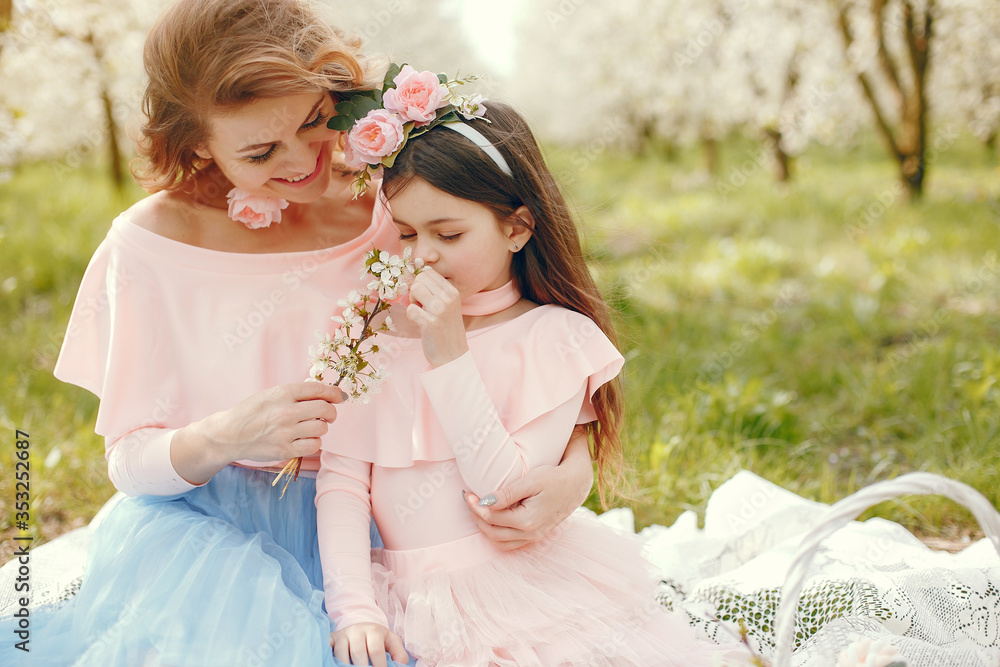 Pretty mother with daughter. Family in a spring park. Woman in a pink dress. Child with a flowers Pretty mother with daughter. Family in a spring park. Woman in a pink dress. Child with a flowers