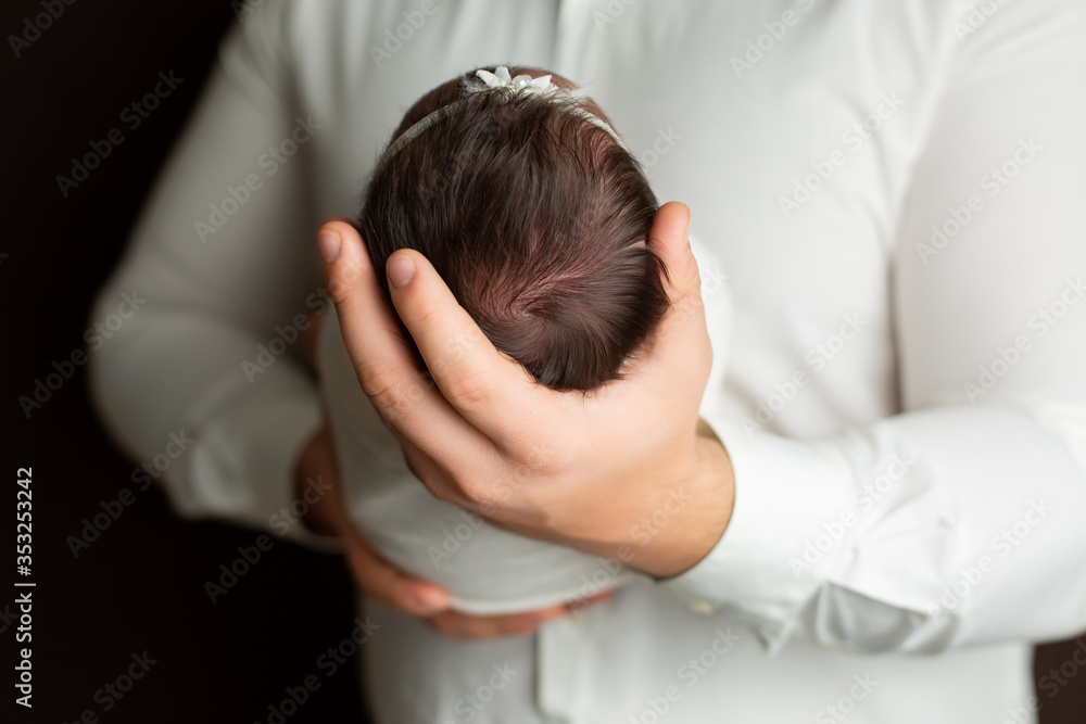 The head of a newborn child in the hands of the father. first photo session of a newborn The head of a newborn child in the hands of the father. first photo session of a newborn