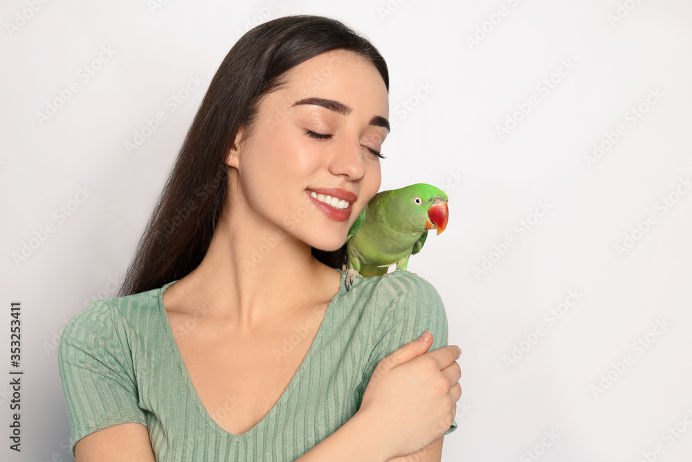 Young woman with Alexandrine parakeet on light background. Cute pet Young woman with Alexandrine parakeet on light background. Cute pet
